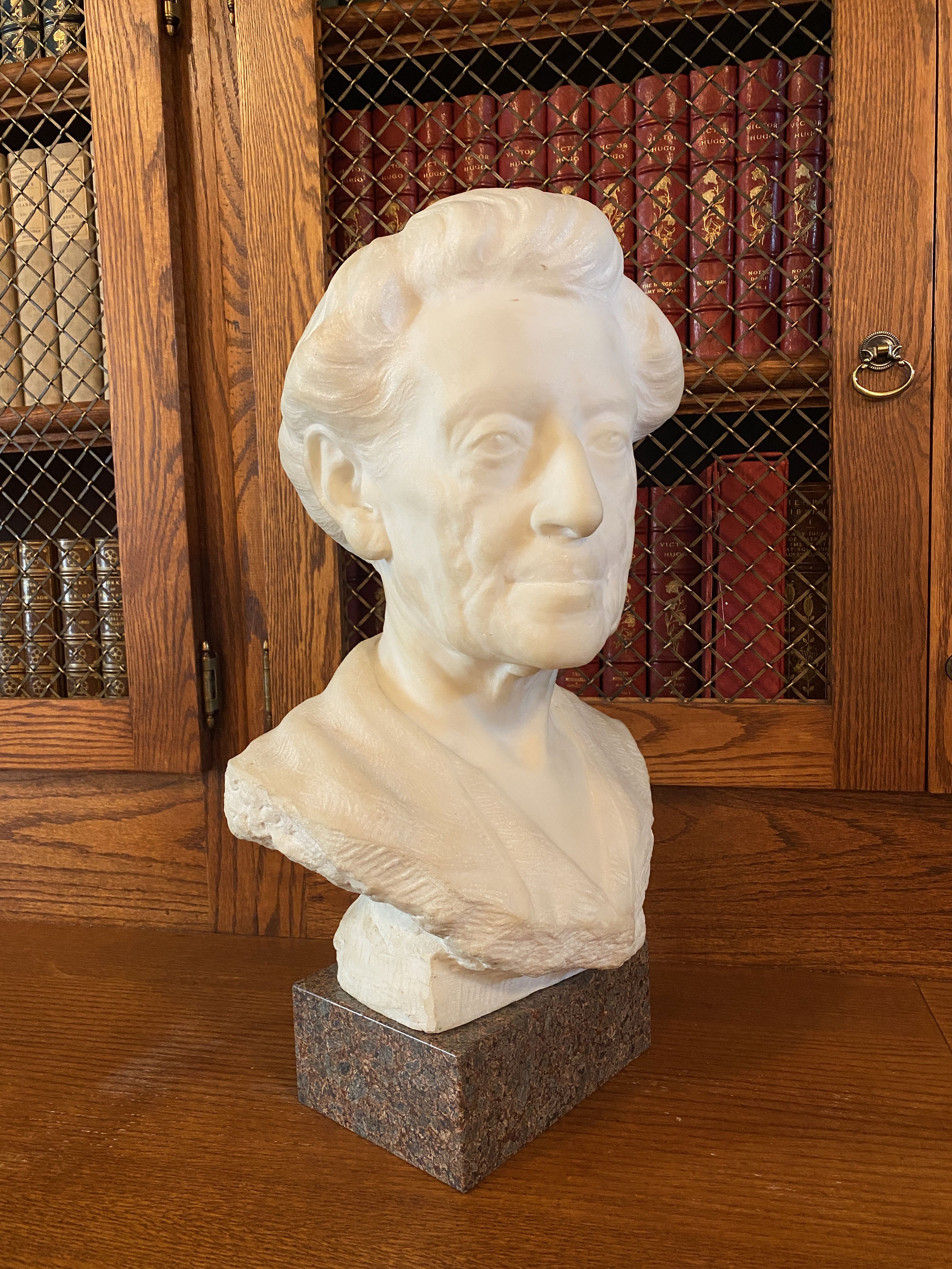 Ellen Browning Scripps marble bust displayed in front of a book collection on shelves.